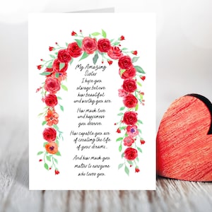 May include: A card with a watercolor floral design of red roses and green leaves. The card has a message that reads "My Amazing Sister I hope you always believe how beautiful and worthy you are. How much love and happiness you deserve. How capable you are of creating the life of your dreams... And how much you matter to everyone who loves you."