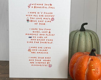 May include: A white card with a handwritten message wishing someone a beautiful fall. The message includes wishes for cozy moments, warm days, and amazing light and colors. The card is decorated with fall-themed illustrations, including leaves, a cup of coffee, and a campfire.