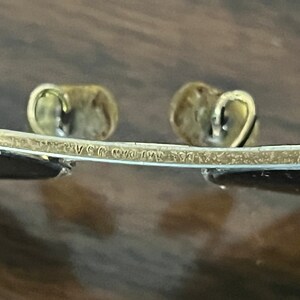 Peut inclure: Gros plan sur l'inscription "Ray-Ban USA" sur la monture en m&eacute;tal dor&eacute; d'une paire de lunettes de soleil.