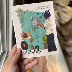 Può includere: Una piccola stampa artistica rettangolare. L'illustrazione mostra una figura che innaffia le piante, con la parola "KIP" sopra. Lo sfondo include un rettangolo turchese, piante e un motivo a scacchiera. Il nome dell'artista e la data sono in basso.