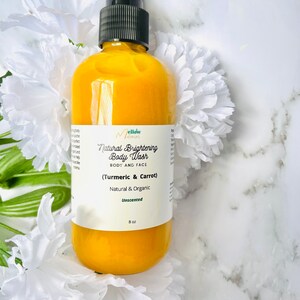 May include: A yellow bottle of Mellow Mama's Natural Brightening Body Wash with Turmeric & Carrot. The bottle is 8 oz and unscented. The bottle is on a white marble surface with white flowers.