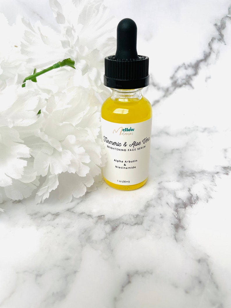 Puede incluir: Una botella de vidrio transparente con un gotero negro lleno de un l&iacute;quido amarillo. La etiqueta de la botella dice "Mellow Turmeric & Aloe Vera Brightening Face Serum" con los ingredientes "Alpha Arbutin & Niacinamide" y "1 oz (30ml)".