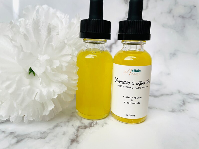 Puede incluir: Dos botellas de vidrio &aacute;mbar con goteros llenas de un l&iacute;quido amarillo. Las botellas est&aacute;n etiquetadas con "Mellow Moments Turmeric & Aloe Vera Brightening Face Serum" con los ingredientes "Alpha Arbutin & Niacinamide" y "1 oz (30ml)".