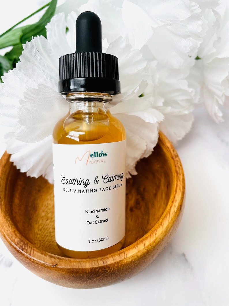 Pu&ograve; includere: Una bottiglia di vetro trasparente con un contagocce nero e un'etichetta bianca. L'etichetta dice "Mellow Melodies" e "Soothing & Calming Rejuvenating Face Serum". Gli ingredienti elencati sono "Niacinamide & Oat Extract". La bottiglia contiene 30 ml di siero.