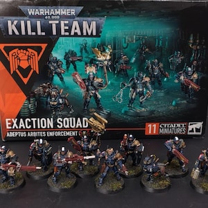Puede incluir: Un set de caja Warhammer 40,000 Kill Team Exaction Squad con personal de cumplimiento de Adeptus Arbites. El set incluye 11 figuras en miniatura pintadas, cada una sobre una base circular, presentadas frente al empaque original.