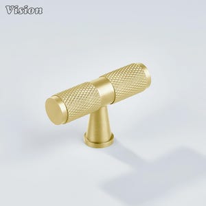 May include: A gold-colored cabinet pull with a diamond pattern on the handle. The pull has a T-shape design, with a cylindrical handle and a conical base. The word "Vision" is in the top left corner.