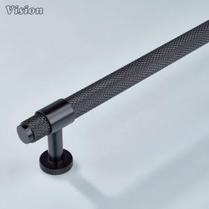 Könnte beinhalten: Ein schwarzer Schrankgriff mit einem strukturierten, rautenförmigen Griff und einem zylindrischen Ende. Der Griff hat ein T-förmiges Design mit einem runden Sockel. Das Wort "Vision" befindet sich in der oberen linken Ecke.