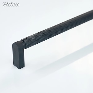 Könnte beinhalten: Ein schwarzer Schrankgriff mit einem strukturierten, rautenförmigen Griff und einem rechteckigen Ende. Das Wort "Vision" befindet sich in der oberen linken Ecke. Hardware für Möbel und Inneneinrichtung.