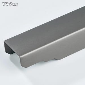 May include: A close-up of a grey metal cabinet pull with a brushed finish. The pull has a rectangular shape with a curved edge and a recessed area on the underside. The word "Vision" is in the upper left corner.