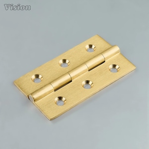 May include: A brass-colored hinge with six screw holes and a central barrel. The hinge is rectangular with rounded corners and a smooth finish. The word "Vision" is in the upper left corner.