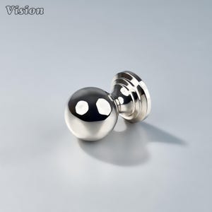 May include: A shiny, silver-colored door knob with a spherical handle and a circular base. The knob reflects light, creating bright spots on its surface. The word "Vision" is in the top left corner.