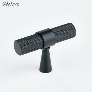 May include: Black cabinet pull with a diamond pattern on the handle. The pull has a cylindrical handle and a conical base. The word "Vision" is in the upper left corner. Suitable for drawers and cabinets.