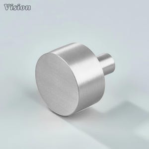 May include: A brushed stainless steel cabinet knob. The knob features a cylindrical body and a smaller, cylindrical stem. The design is simple and modern, suitable for drawers or cabinet doors. The word "Vision" is in the top left corner.
