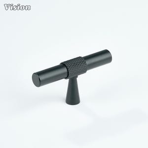 May include: A black cabinet pull with a textured center section and cylindrical ends. The pull is mounted on a conical base. The word "Vision" is in the upper left corner.