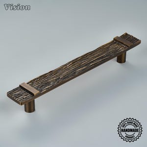 May include: A long, rectangular cabinet pull handle with a dark bronze finish and a textured, wood-grain surface. The handle features two smooth, flat bands near the ends and two cylindrical mounting posts on the underside for attachment.