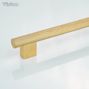 May include: A gold-colored cabinet pull with a textured, diamond-patterned handle. The handle is cylindrical and attached to a square base. The word "Vision" is in the upper left corner.