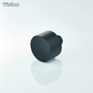 May include: A black cylindrical object with a flat top and a smaller, rounded extension. The object is set against a white background, with the word "Vision" in the upper left corner.