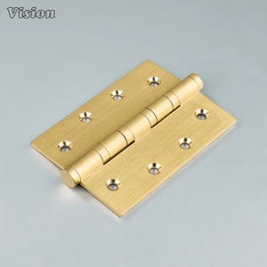 May include: A brass-colored door hinge with a rectangular shape and rounded edges. The hinge has multiple screw holes and a cylindrical barrel in the center. The word "Vision" is in the top left corner.
