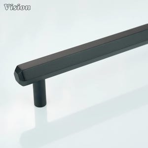 Könnte beinhalten: Ein schwarzer Schrankgriff mit geometrischem Design. Der Griff hat eine rechteckige Stange mit facettiertem Ende und einen zylindrischen Pfosten. Das Wort "Vision" befindet sich in der oberen linken Ecke.