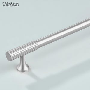 Op de afbeelding: Een geborstelde zilveren kastgreep met een cilindrische handgreep en een geribbelde grip. De greep is gemonteerd op een kleine, uitlopende basis. Het woord "Vision" staat in de linkerbovenhoek. Geschikt voor keuken- of badkamerkasten.