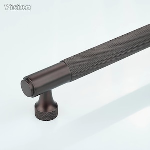 Può includere: Una maniglia per armadio in bronzo scuro con una maniglia strutturata a motivo diamantato. La maniglia presenta un design cilindrico con un'estremità arrotondata e una base decorativa. La parola "Vision" è nell'angolo in alto a sinistra.