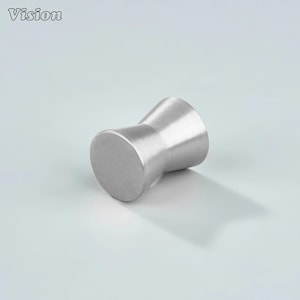 Può includere: Un pomello per mobili in metallo spazzolato con una forma a clessidra unica. Il pomello ha una base e una parte superiore cilindriche, collegate da un centro curvo più stretto. La parola "Vision" è stampata in alto a sinistra.