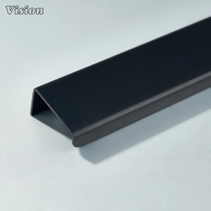 May include: A black metal cabinet pull with a curved edge. The pull is a dark matte black and has a simple, modern design. The word "Vision" is in the upper left corner.