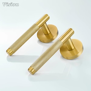 May include: Two gold-colored door handles with a textured grip and a round base. The handles are cylindrical with a textured pattern. The word "Vision" is in the top left corner.
