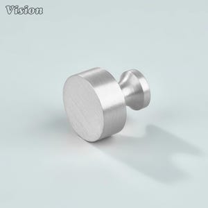 May include: A brushed silver cabinet knob with a cylindrical body and a smaller, rounded stem. The knob is made of metal and has a matte finish. The word "Vision" is in the top left corner.