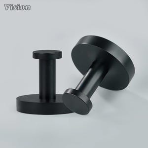 May include: Two black metal wall hooks. Each hook has a circular base and a cylindrical post topped with a smaller circular head. The hooks are designed for hanging items and have a matte finish. The word "Vision" is in the top left corner.
