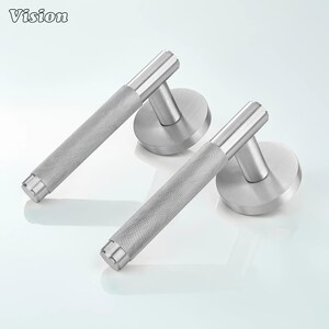 May include: Two brushed nickel door handles with a textured grip and round backplates. The word "Vision" is in the top left corner. The handles are designed for a modern aesthetic.