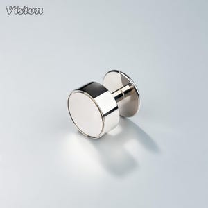 May include: A silver-colored cufflink with a circular face and a post. The cufflink has a shiny, reflective surface. The word "Vision" is in the upper left corner.