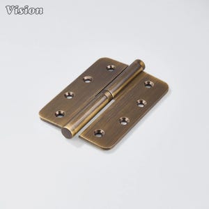 May include: A bronze-colored door hinge with rounded corners and multiple screw holes. The hinge is open, revealing the cylindrical pin that connects the two rectangular plates. The word "Vision" is in the upper left corner.