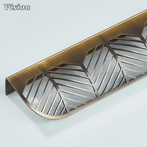 May include: A bronze-colored cabinet pull with a leaf-like cut-out design. The Vision logo is visible in the upper left corner. The pull has a curved shape and is likely made of metal.