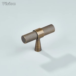 May include: A bronze-colored cabinet pull with a diamond-patterned handle. The pull has a cylindrical handle, a circular band, and a conical base. The word "Vision" is in the top left corner.