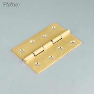 Puede incluir: Una bisagra de color latón con forma rectangular y múltiples orificios para tornillos. La bisagra está compuesta por dos placas rectangulares conectadas por un pasador cilíndrico. La palabra "Vision" está en la esquina superior izquierda.