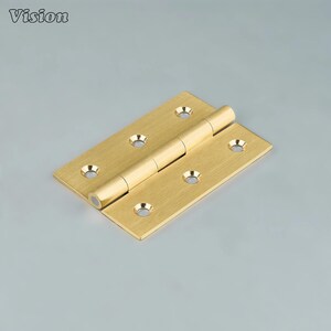 May include: A brass hinge with a rectangular form and circular screw holes. The hinge is open, showing the cylindrical pin connecting the two rectangular leaves. The word "Vision" is in the top left corner.