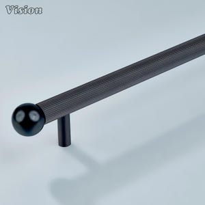 Peut inclure: Une poignée de meuble en métal noir et nervuré, avec une extrémité sphérique et un support cylindrique. La poignée est conçue avec une série de rainures parallèles sur toute sa longueur. Le mot "Vision" est dans le coin supérieur gauche.