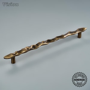 May include: A long, horizontal cabinet pull handle with a dark bronze finish and a textured, wavy, undulating surface. The handle is supported by two cylindrical posts at each end. The word Vision is in the top left corner and a badge is in the bottom right.