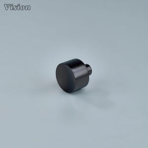 May include: A black cylindrical object with a small, rounded knob on one end. The object has a matte finish and is set against a light gray background. The word "Vision" is in the upper left corner.