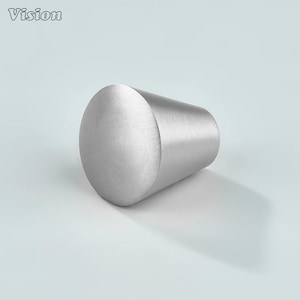 May include: A brushed metal cabinet knob with a cylindrical shape and a rounded end. The word "Vision" is in the upper left corner. The knob is silver and casts a shadow on a light blue surface.