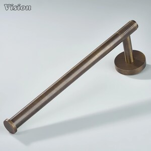Può includere: Un portasciugamani color bronzo con un supporto a parete circolare e una barra cilindrica. La barra ha un design a coste su un'estremità. La parola "Vision" è nell'angolo in alto a sinistra.