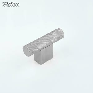 May include: A silver-colored cabinet knob with a textured, cylindrical handle and a square base. The handle has a diamond pattern. The word "Vision" is in the upper left corner.