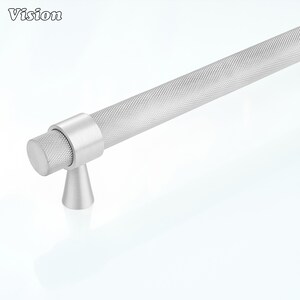 May include: A silver-toned metal cabinet handle featuring a long, cylindrical bar with a textured, diamond-patterned knurled surface. The handle is supported by a smooth, conical base and includes a matching knurled end cap on the visible side.