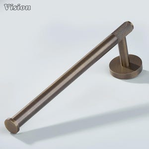 May include: A bronze-colored towel bar with a circular base and a textured end. The bar is designed for wall mounting and has a simple, modern aesthetic. The word "Vision" is in the top left corner.