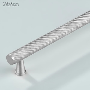 May include: A silver cabinet pull with a textured, diamond-patterned grip. The pull has a cylindrical handle and a conical base. The word "Vision" is in the upper left corner.
