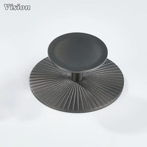 May include: A dark grey metal cabinet knob with a circular top and a textured, ridged base. The word "Vision" is printed in the upper left corner. The knob is designed for furniture and home decor.