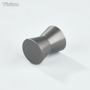 Può includere: Un pomello per armadio in metallo grigio scuro con base cilindrica e parte superiore conica. Il pomello ha una finitura liscia e opaca ed è progettato per una facile presa. La parola "Vision" è nell'angolo in alto a sinistra.