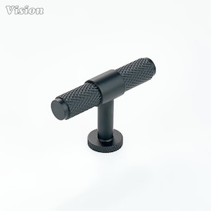 May include: A black cabinet pull with a textured, diamond-patterned handle. The handle is cylindrical and attached to a short, vertical post and a circular base. The word "Vision" is in the upper left corner.