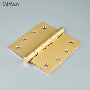 May include: A brass door hinge with a brushed finish. The hinge is rectangular with rounded corners and has multiple screw holes. The barrel of the hinge is cylindrical and connects the two rectangular plates. The word "Vision" is in the top left corner.